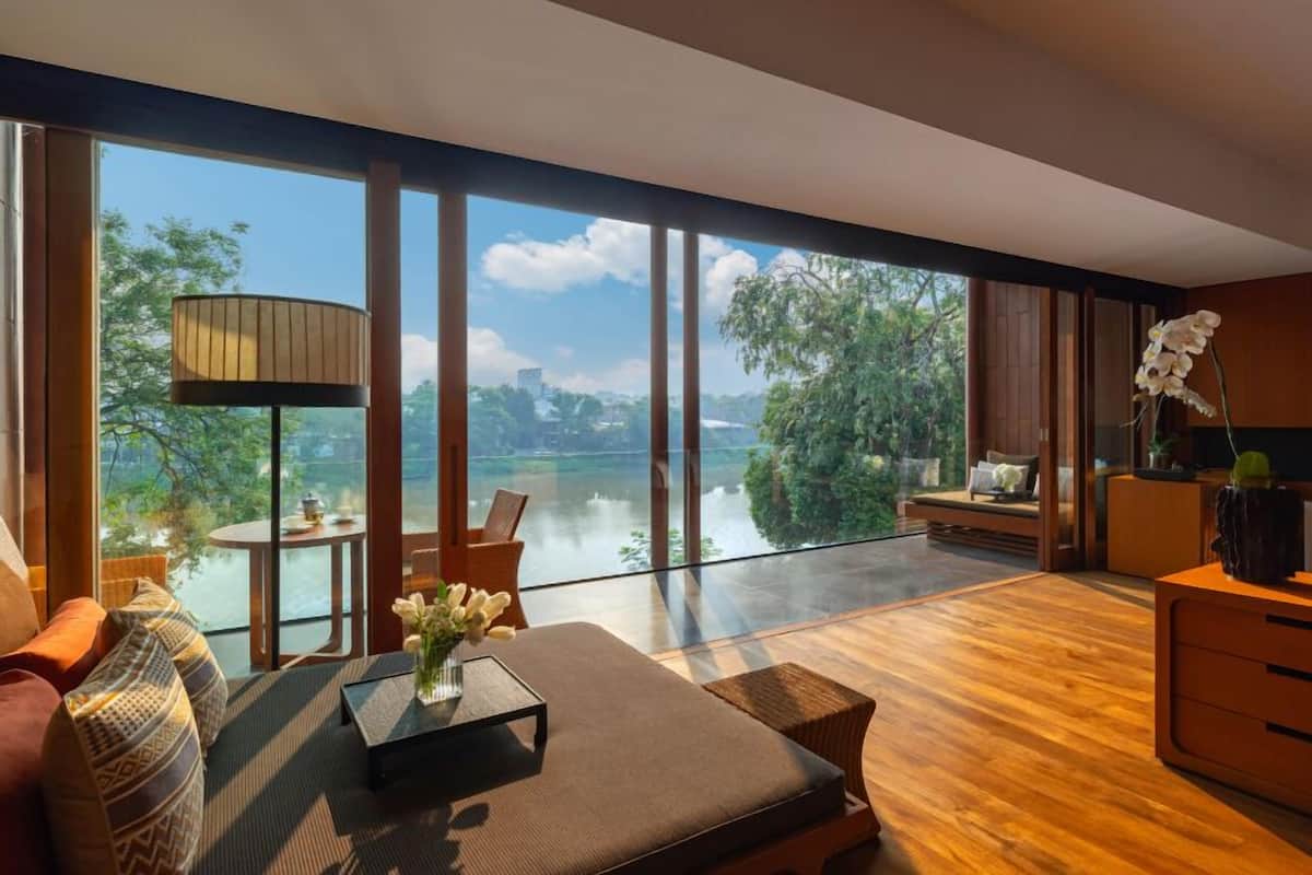 A modern living room with a large window overlooking a body of water and greenery.