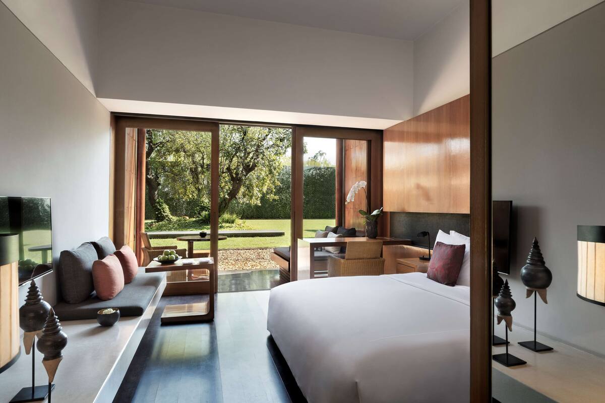 A modern bedroom with a large bed, a desk, and a seating area.