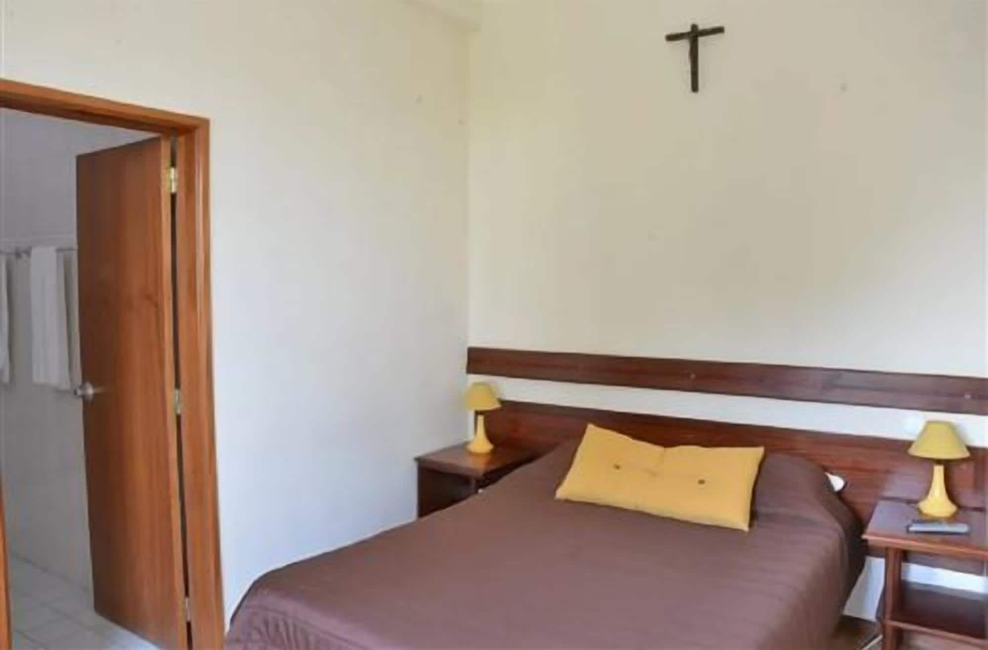 A bedroom with a bed, two bedside tables, and a door leading to a bathroom.