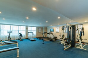 Un gimnasio con cintas de correr, elípticas y equipos de levantamiento de pesas.