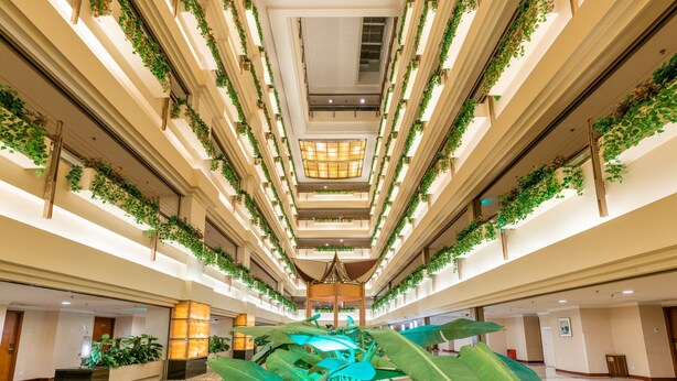 A multi-level atrium with a central open space, surrounded by balconies with greenery.