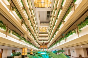 A multi-level atrium with a central open space, surrounded by balconies with greenery.