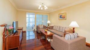 A living room with a sofa set, a coffee table, a TV, and a desk with a lamp.