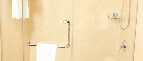 A glass-enclosed shower stall with a towel rack, a handheld showerhead, and a toilet paper holder.