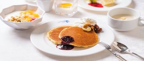 Desayuno con tortitas, fruta y bebidas.