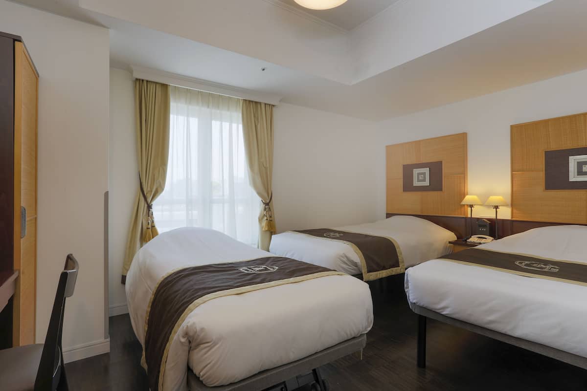 A hotel room with two beds, a desk, and a chair.
