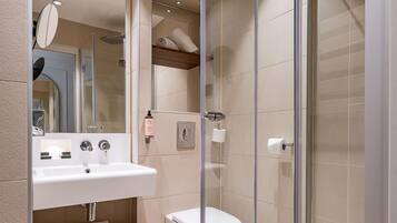 Une salle de bain moderne avec une douche à parois de verre, un lavabo blanc et un miroir.