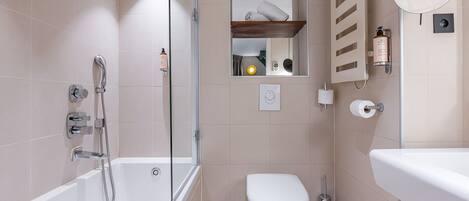 A modern bathroom with a glass-enclosed shower, a toilet, and a sink.