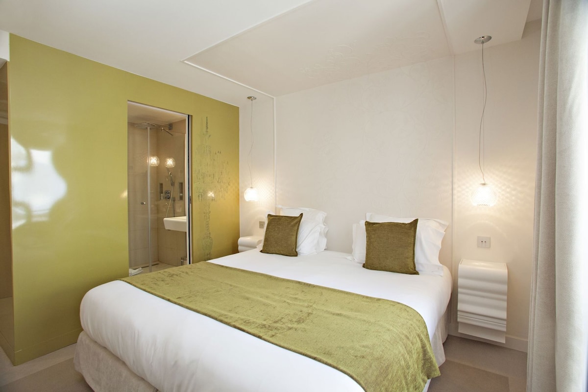 A hotel room with a bed, a bathroom, and a shower.