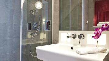 A modern bathroom with a glass-enclosed shower, a white sink, and a large mirror with two round lights.
