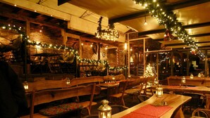Un restaurante acogedor con mesas y bancos de madera, luces colgantes y faroles.