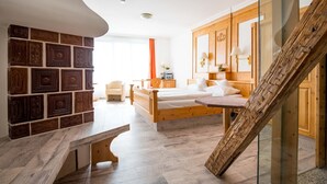 Un dormitorio con cama de madera, un banco, pared con azulejos decorativos, escalera de cristal y vistas al exterior.
