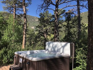 A hot tub in a forested area with a sign indicating it is for adults only. - Rocky Mountain Lodge (Cascade)