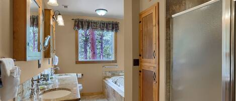 A bathroom with a double sink vanity, a bathtub, a shower, and a frosted glass door.