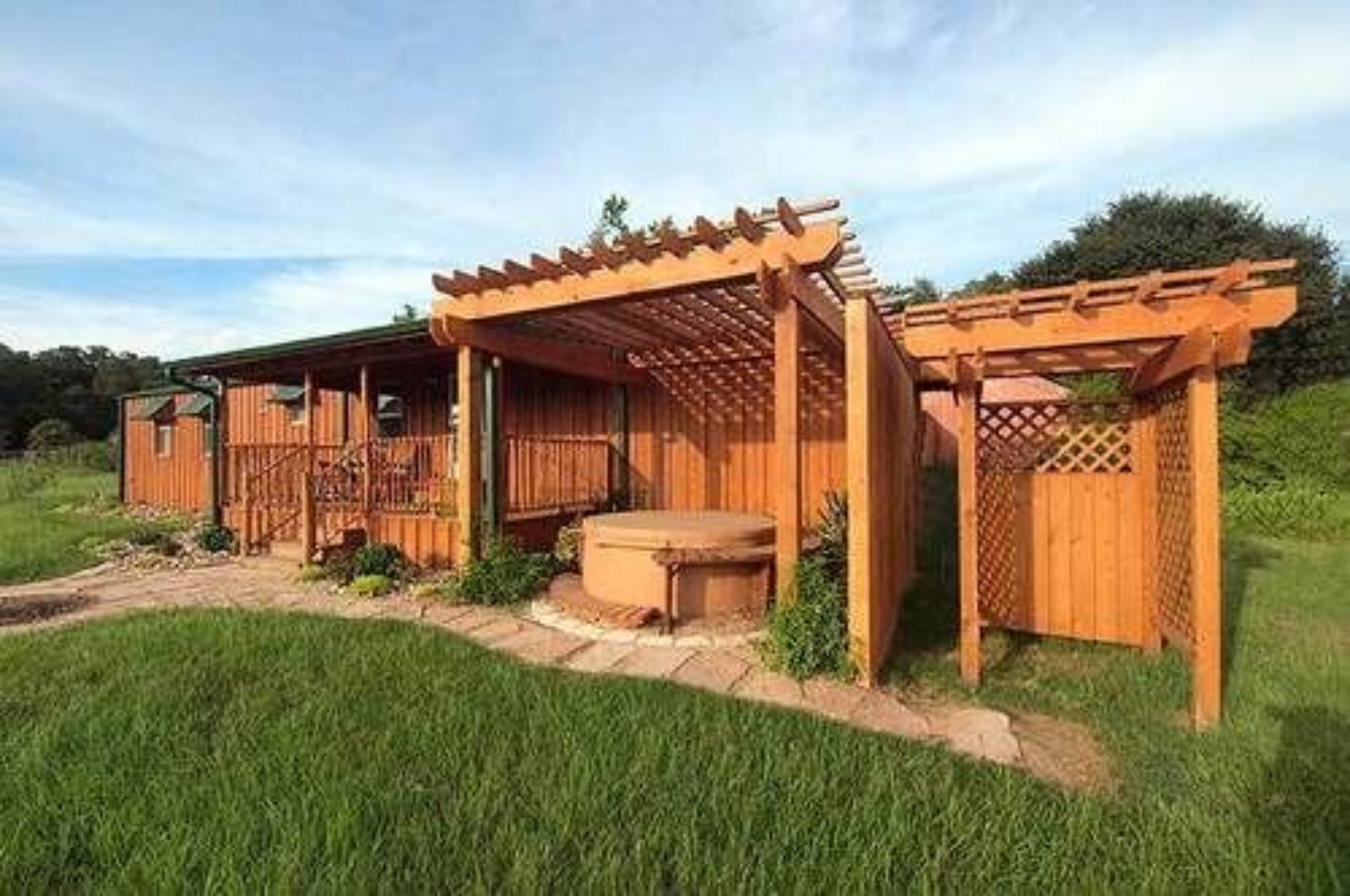 Una estructura de madera con una pérgola y un pequeño espacio al aire libre para sentarse.