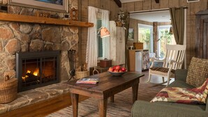 A cozy room with a stone fireplace, wooden furniture, and a view of the outdoors.