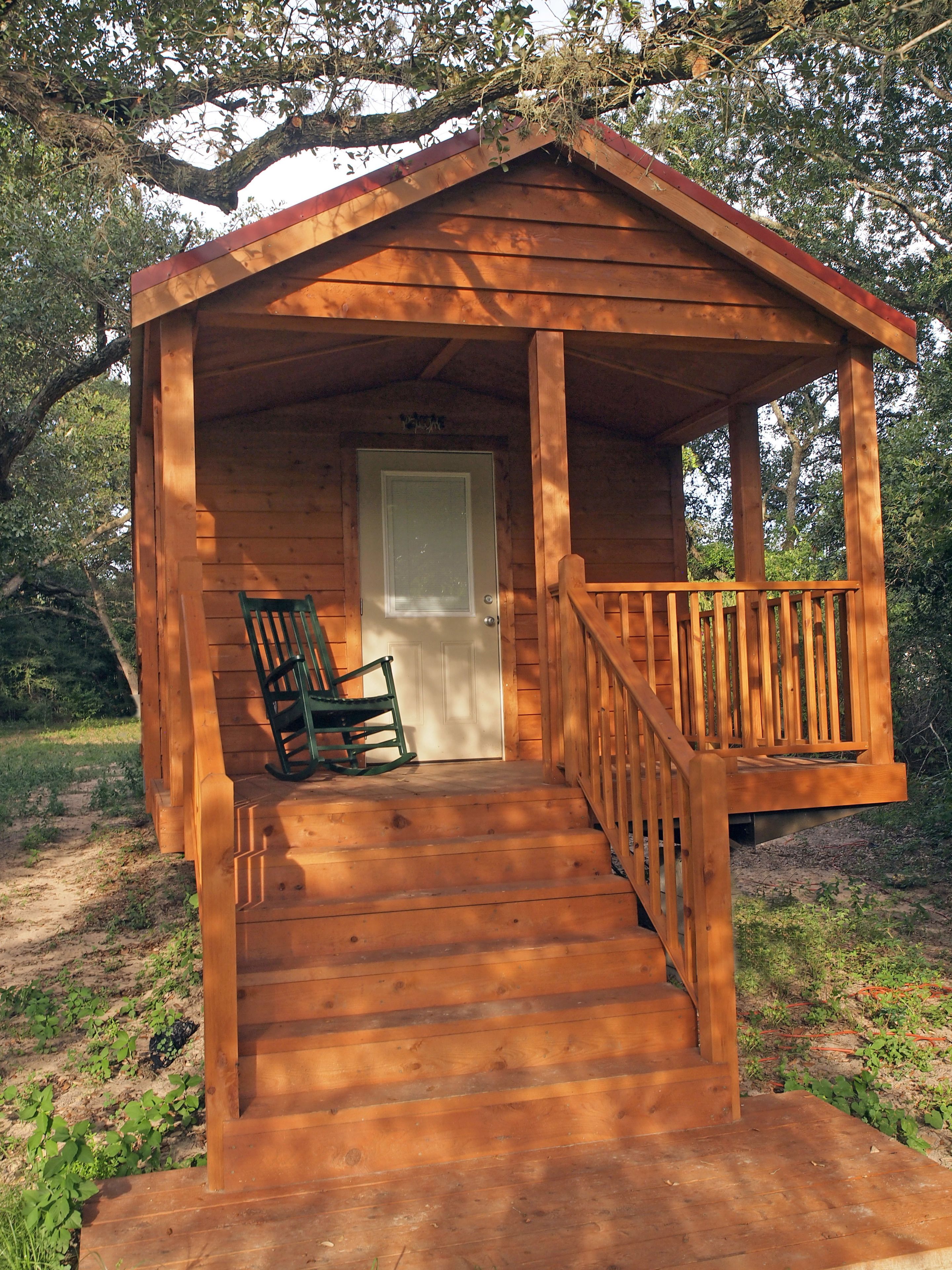 A wooden cabin with a porch, a door, and a rocking chair.