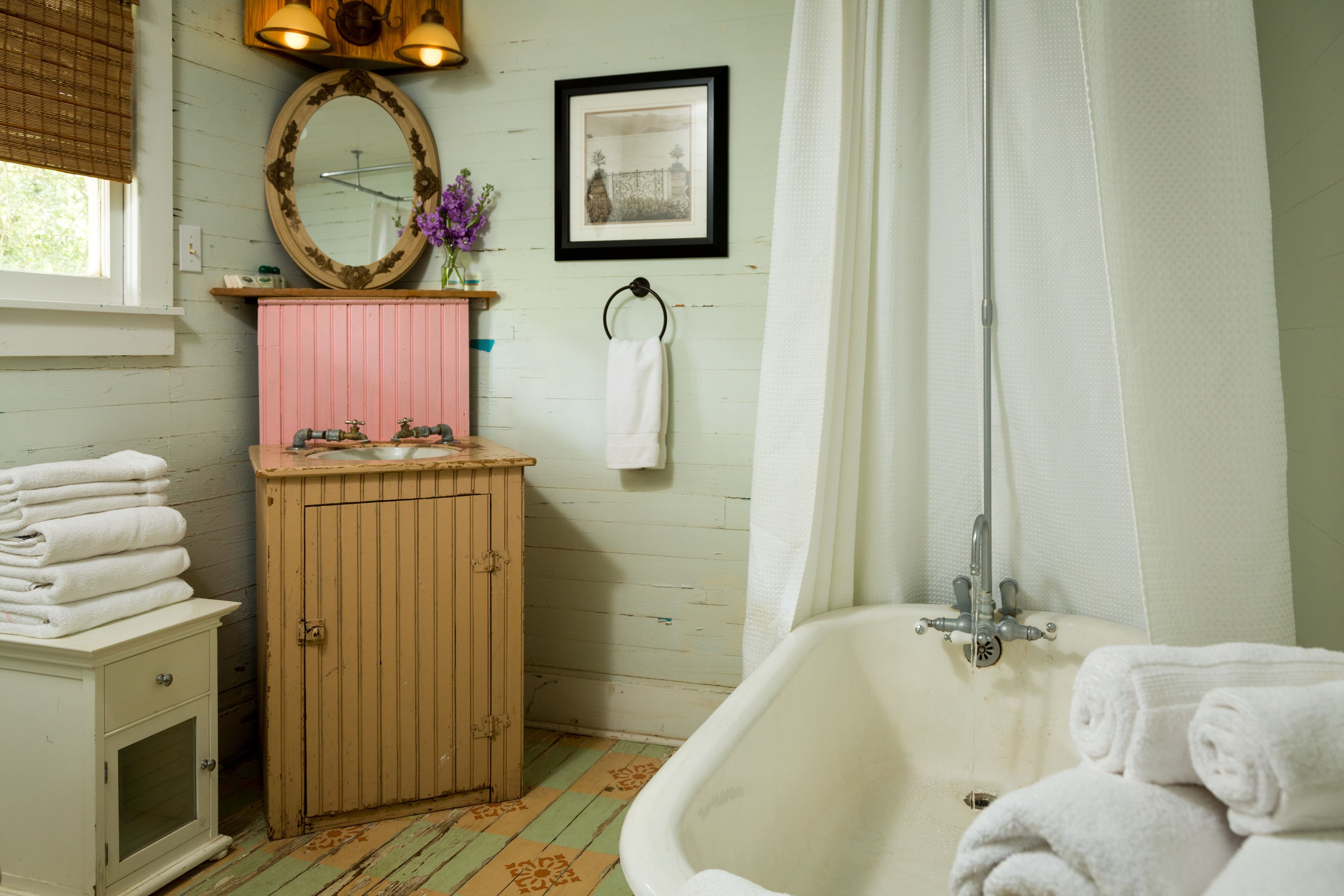 A bathroom with a bathtub, a wooden cabinet, a sink, and a mirror.