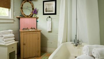 A bathroom with a bathtub, a wooden cabinet, a sink, and a mirror.
