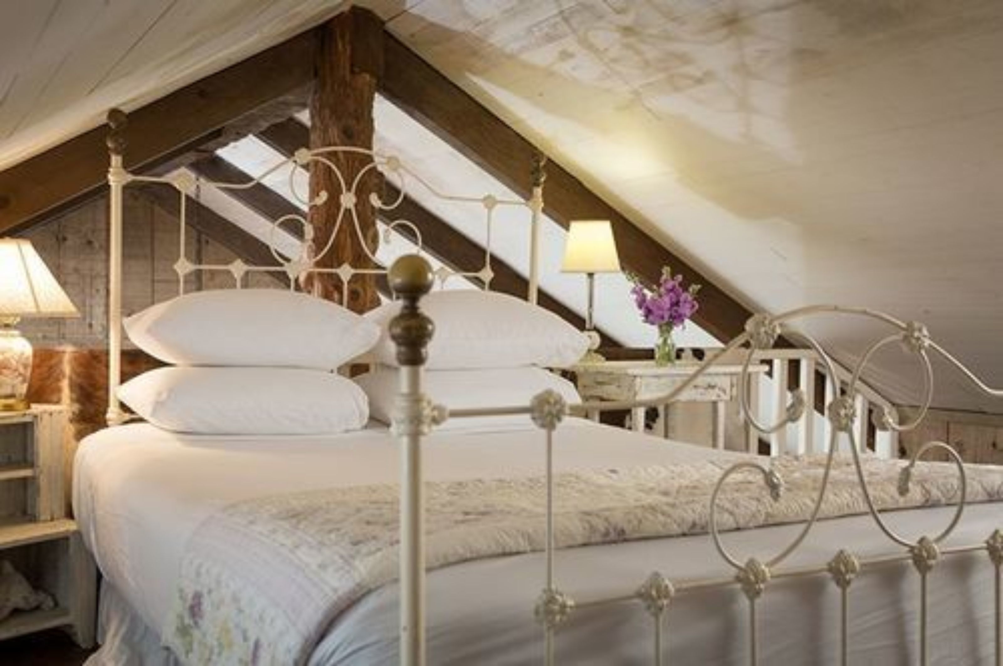 Une chambre à coucher avec un lit à baldaquin, un plafond en bois et une table de chevet avec une lampe.