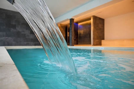Ein Pool mit Wasserfall, Innenbeleuchtung und einer Steinwand im Hintergrund.. Canyamel Classic & Spa, solo Adultos