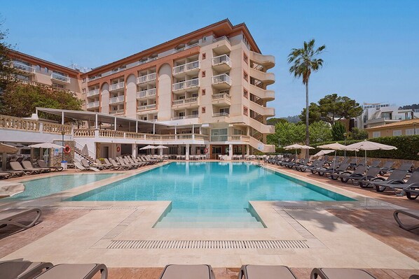 A hotel with a swimming pool, sun loungers, and a palm tree. - Canyamel Classic & Spa, solo Adultos (Capdepera)