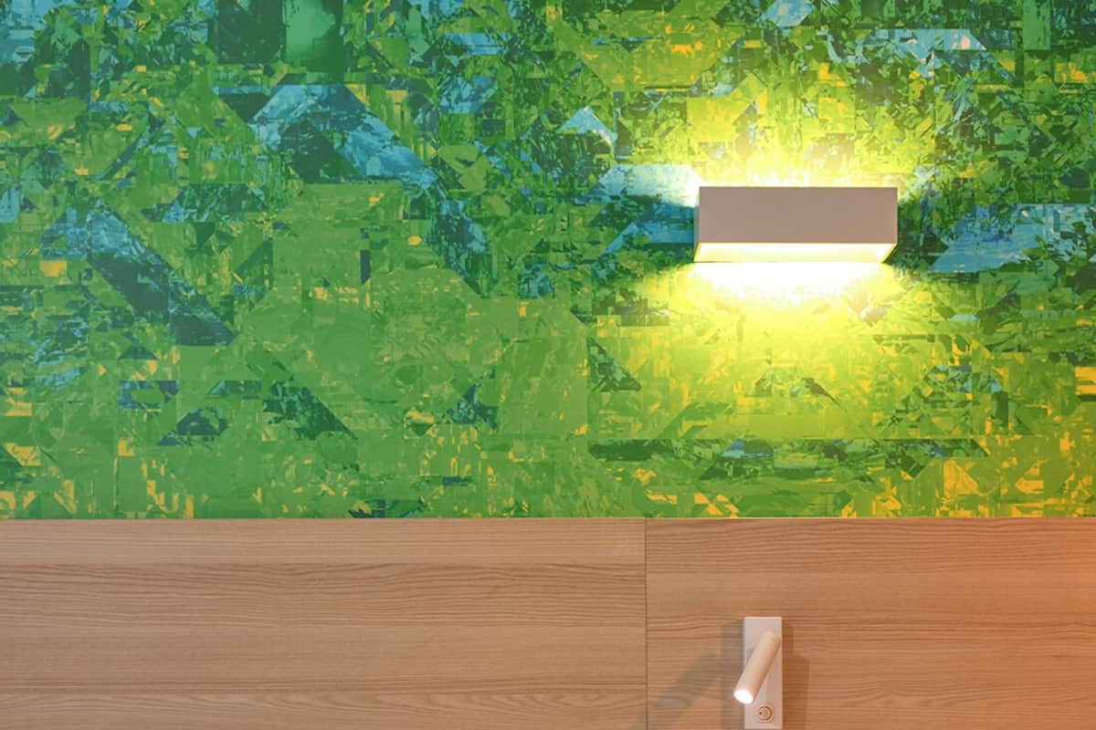 A bedroom with a bed, a green toilet, and a wall-mounted light fixture.