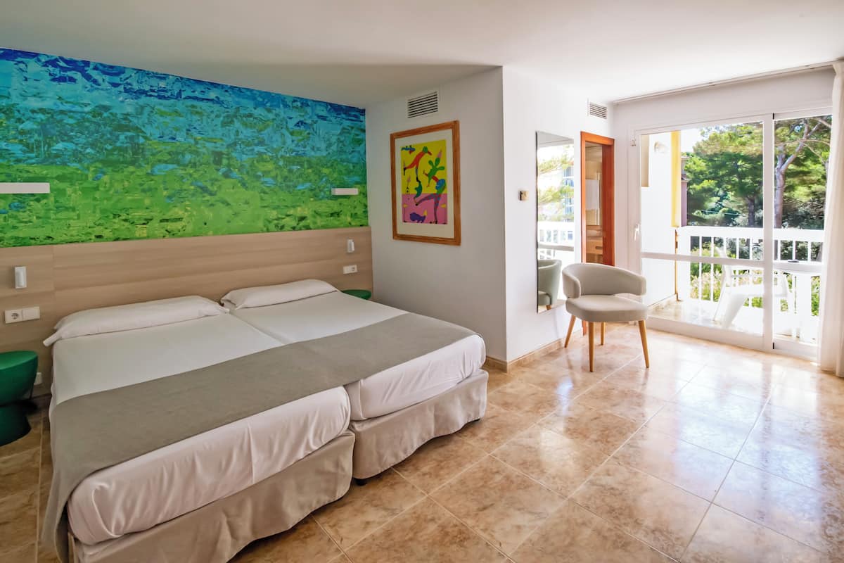 A bedroom with a large bed, a chair, a painting, and a balcony with a view.