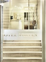 Entrada de um hotel com porta de vidro exibindo o nome "HOTEL ADRIAN".