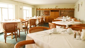 A dining area with multiple tables and chairs, each set with white tablecloths and white tableware. - Adrian Hotel (Athens)