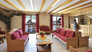 Ein gemütliches Zimmer mit Holzmöbeln, einer Holzbalkendecke und Bergblick durch große Fenster.