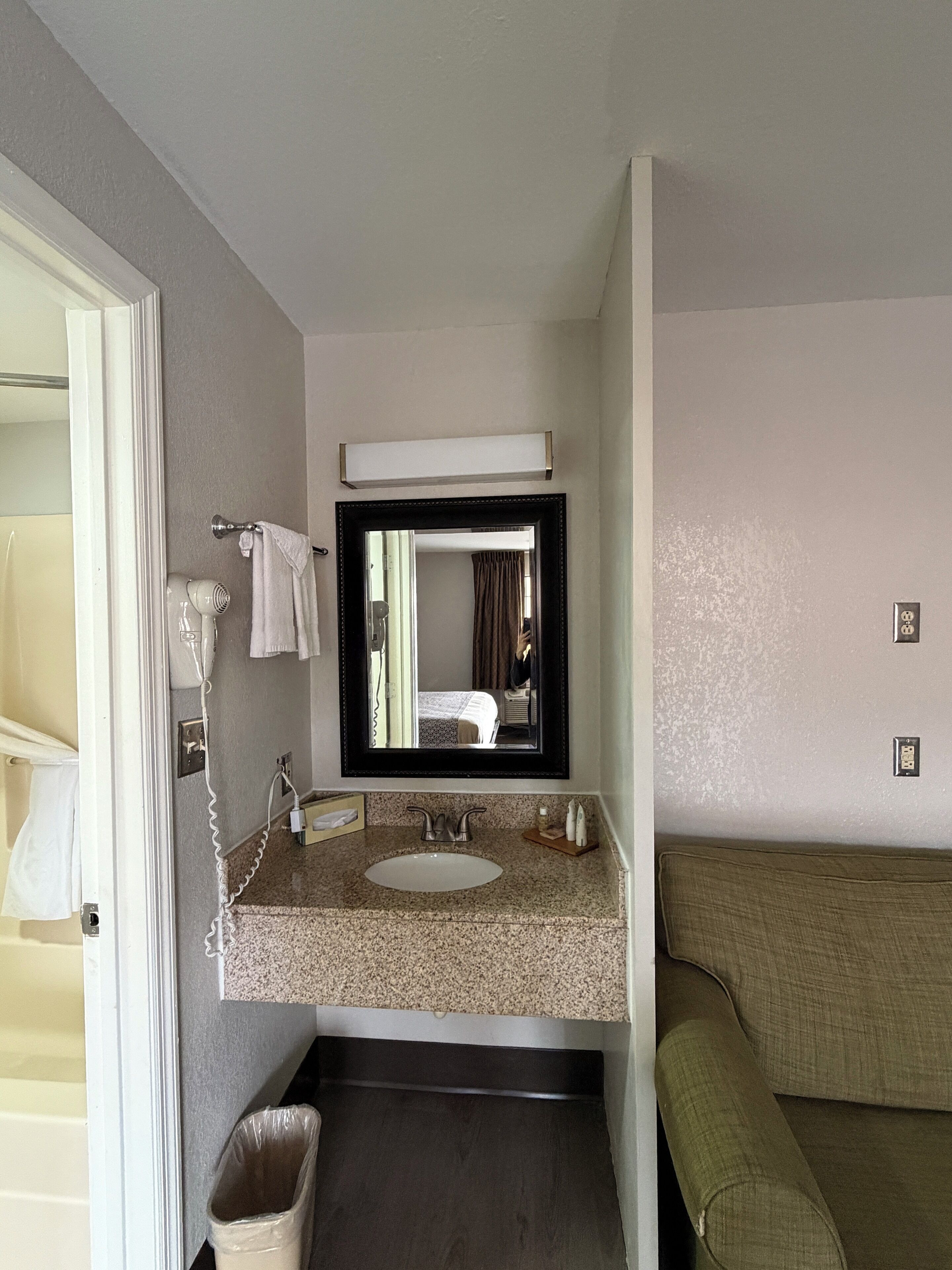 A hotel bathroom with a sink, mirror, and towel rack.