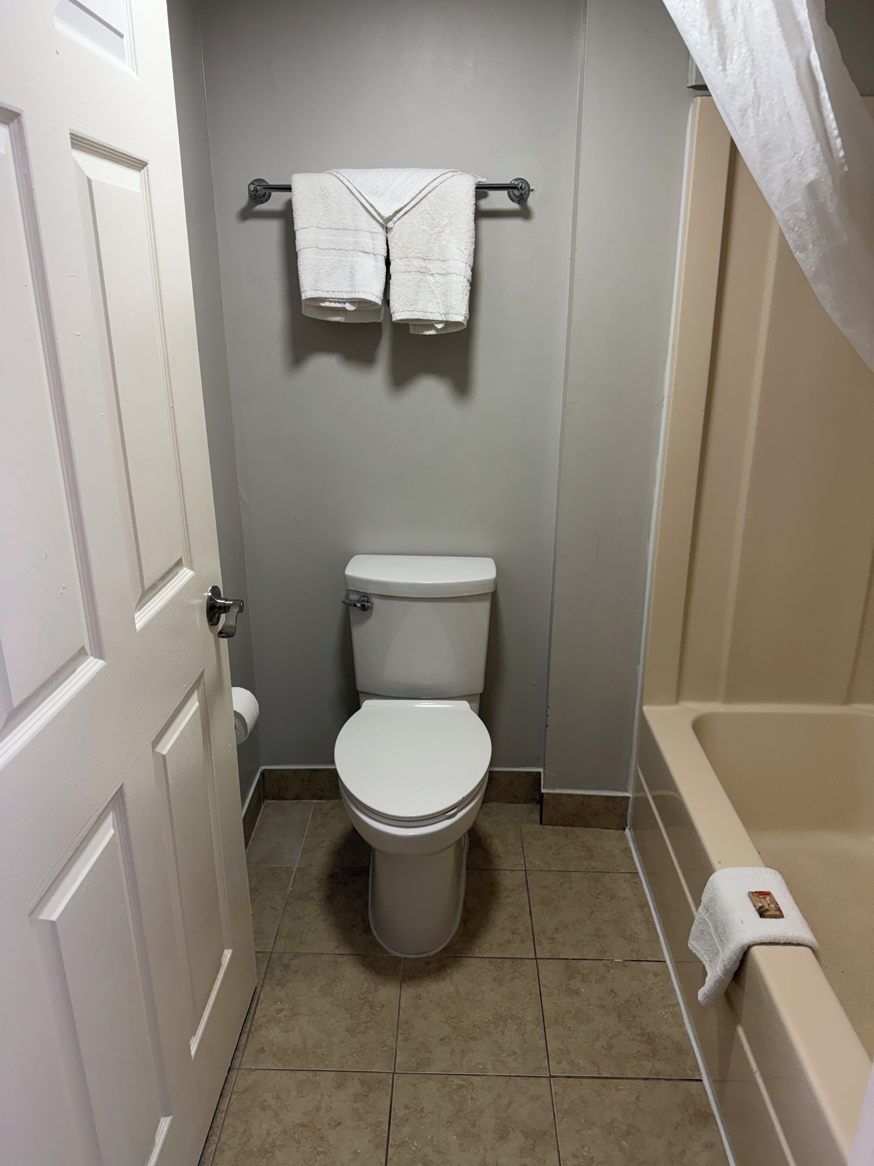Une petite salle de bain comprenant des toilettes, un porte-serviettes avec deux serviettes et une baignoire.