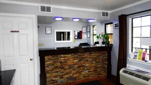 A reception area with a brick wall, a white door, and a window with blinds.