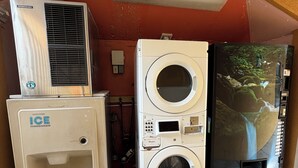 A utility room with an ice dispenser, a stacked washer and dryer, and a water heater.