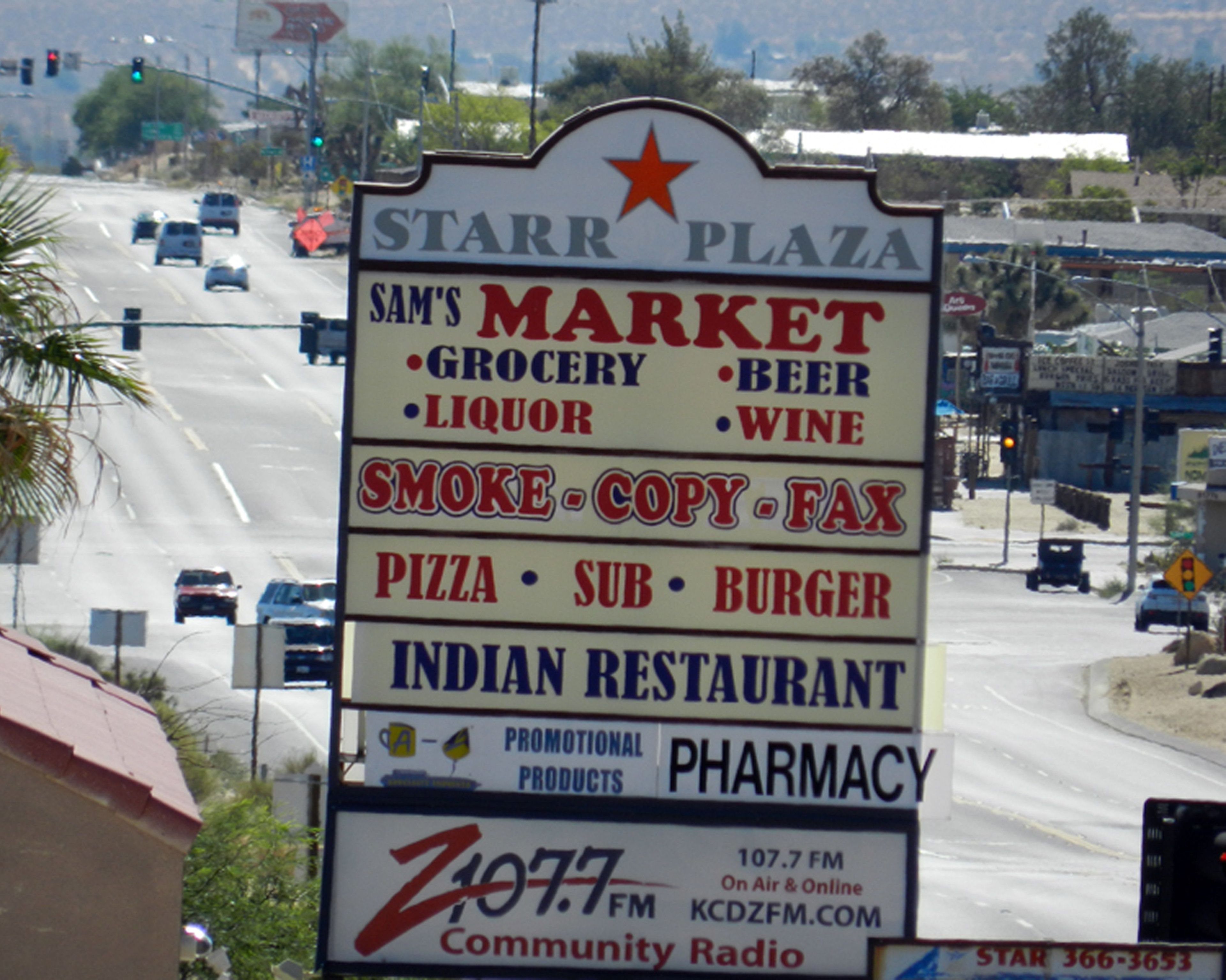 A sign for Starr Plaza with listings for Sam's Market, Smoke-Copy-Fax, Pizza, Sub, Burger, Indian Restaurant, and Pharmacy.
