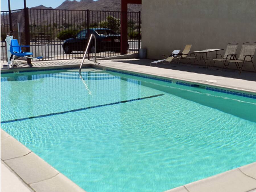 Una piscina con agua azul cristalina, un trampolín y sillones de descanso.