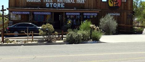 Una tienda llamada Joshua Tree National Park Store con carteles que indican libros, mapas, juguetes, dulces, recuerdos, equipo, regalos y salas de exhibición.