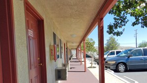 A motel corridor with red doors, numbered room signs, and a covered walkway. - High Desert Motel Joshua Tree National Park (Joshua Tree)