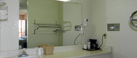 Un baño con lavamanos, espejo, toallero y secador de pelo.