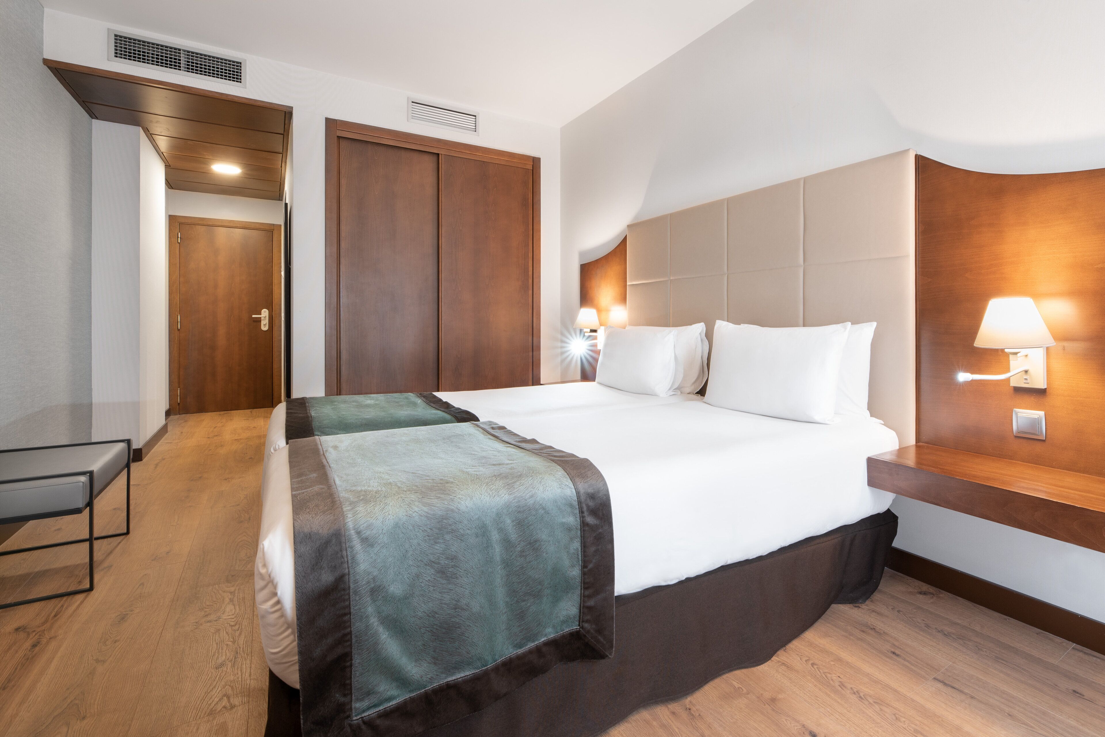 Una habitación de hotel con una cama grande, una mesita de noche, un escritorio y un armario.