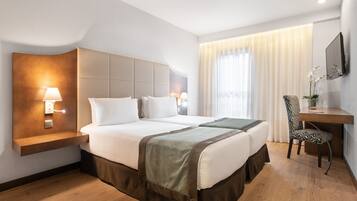 A hotel room with a large bed, bedside tables, a desk, and a chair.