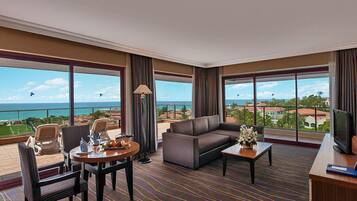 Habitación de hotel con balcón, sofá, mesa de comedor y televisión.