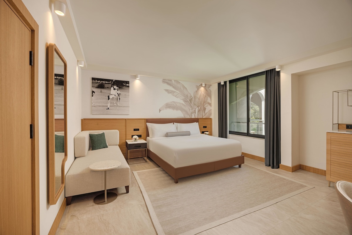 Een moderne hotelkamer met een bed, een slaapbank, een klein tafeltje en een nachtkastje.
