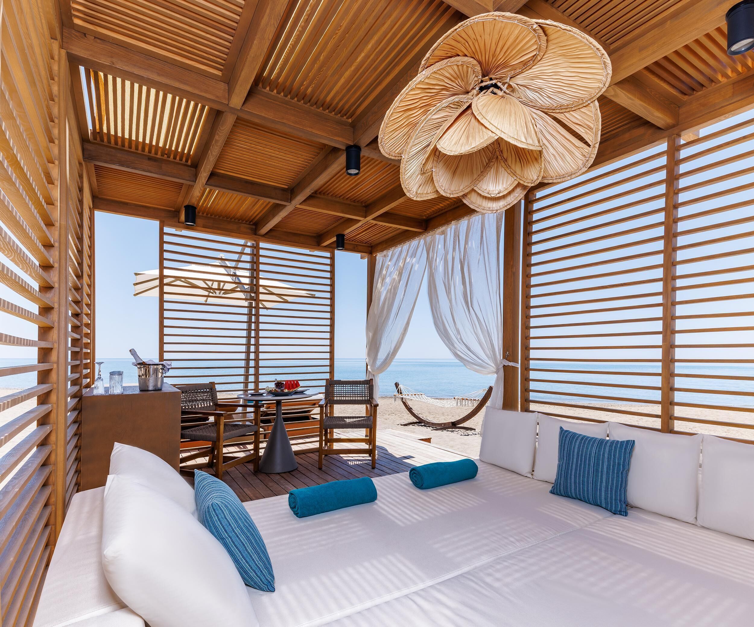 Habitación frente a la playa con una cama grande, una mesa con sillas y vista al mar.