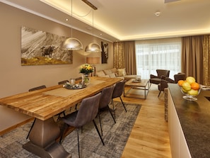 A modern dining area with a wooden table, chairs, and a vase of flowers. - A-VITA Living Luxury Appartements (Seefeld in Tirol)