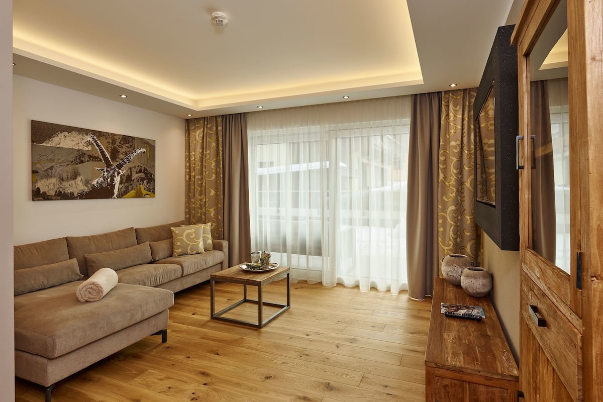 A modern living room with a sofa, coffee table, and a flat-screen TV mounted on a wooden cabinet.