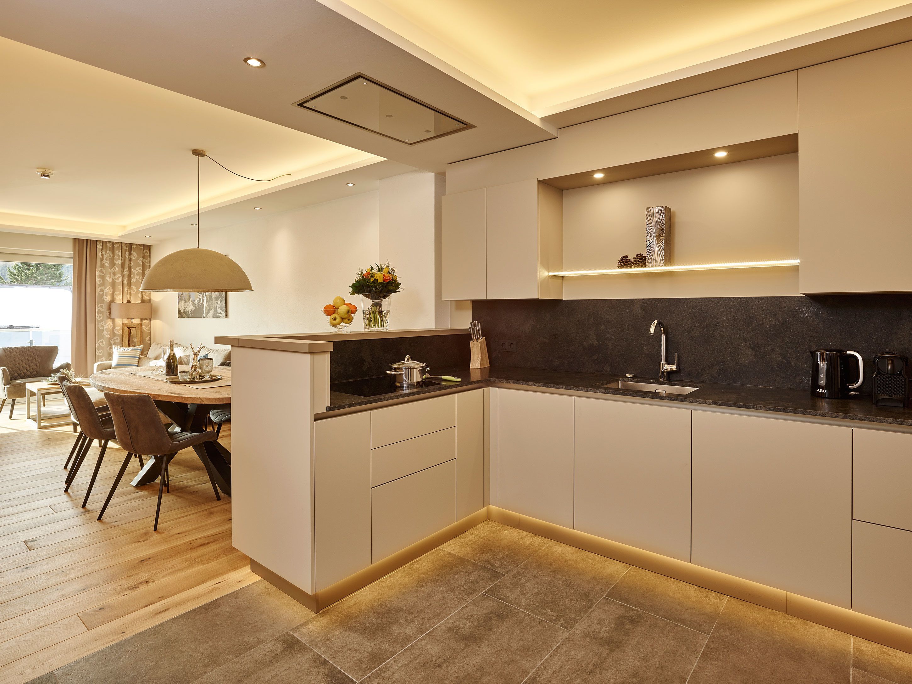 A modern kitchen with a central island, built-in appliances, and a dining area with a table and chairs.