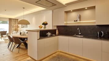 A modern kitchen with a central island, built-in appliances, and a dining area with a table and chairs.