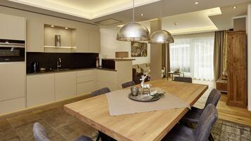 Una cocina moderna con electrodomésticos integrados, un comedor con mesa y sillas de madera, e iluminación colgante.